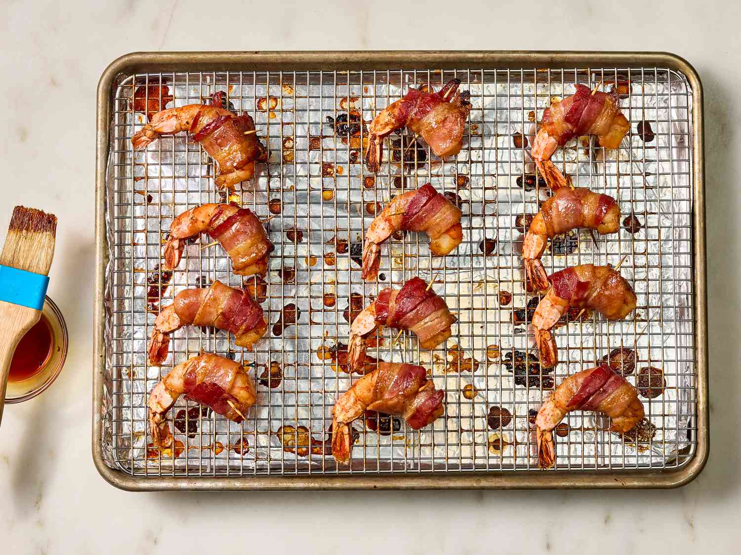 brushing shrimp for a third time with honey mixture on a rack on a sheet pan 