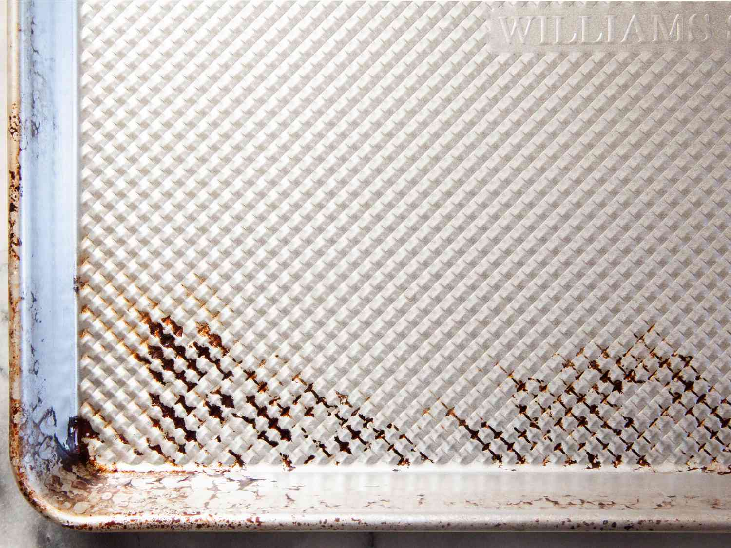 A closeup of the ridged surface of the Williams-Sonoma half-sheet pan with dark splotches after use