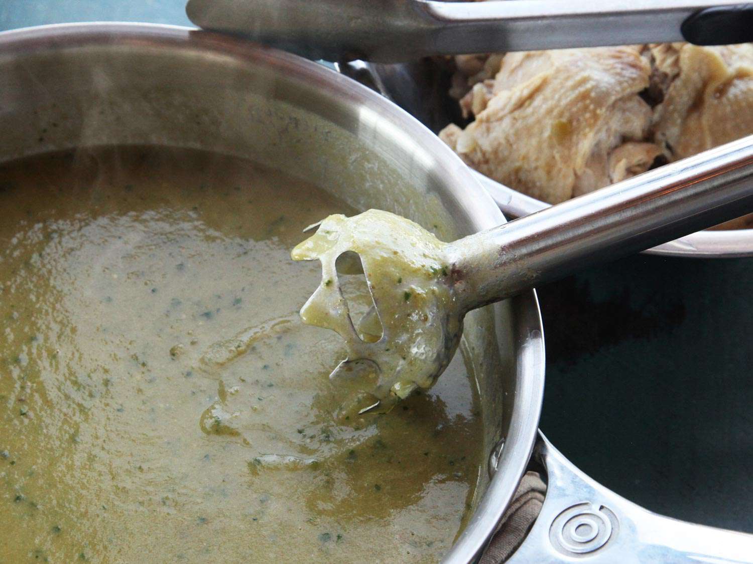 Pureeing chicken green chili (chile verde) sauce in a pot using a hand blender.