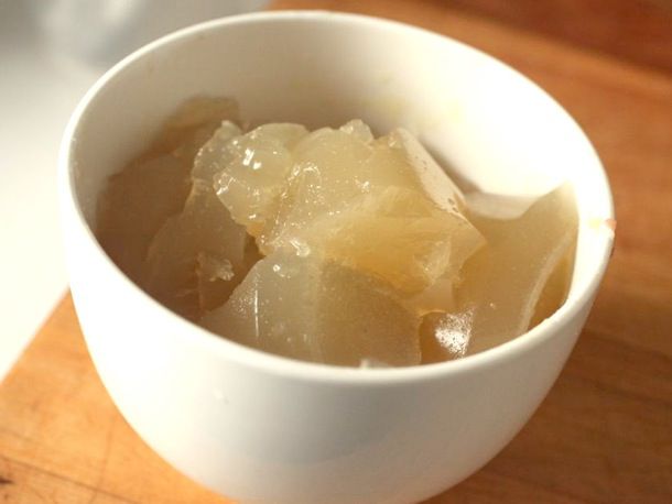 Chunks of gelatinized stock in a white prep bowl.