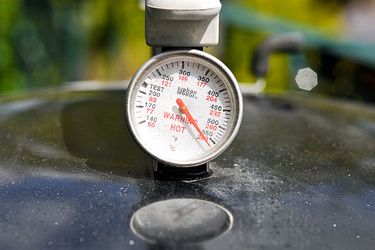 A thermometer on top of a grill. 