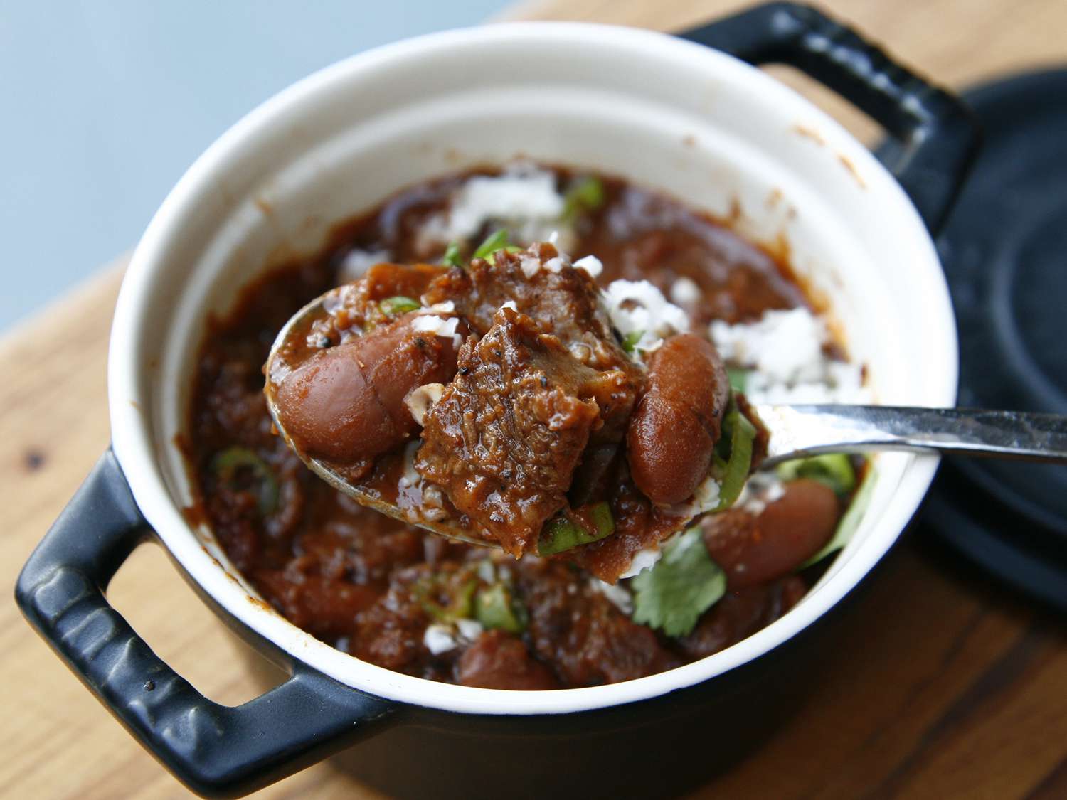 A small crock of The Best Chili Ever, a Serious Eats chili recipe with beans, cilantro and cheese. 