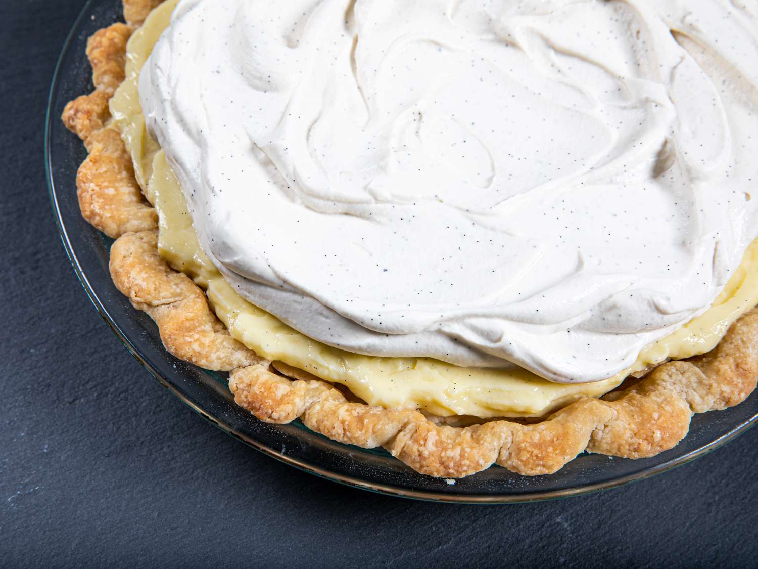 Angled view of banana cream pie, showcases off layers of crust, pie, and whipped cream