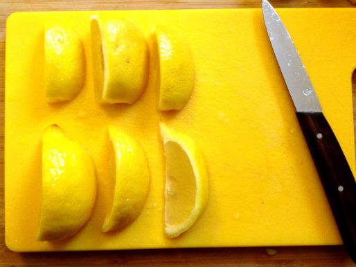 Cut and cleaned lemon wedges on a cutting board with a knife.