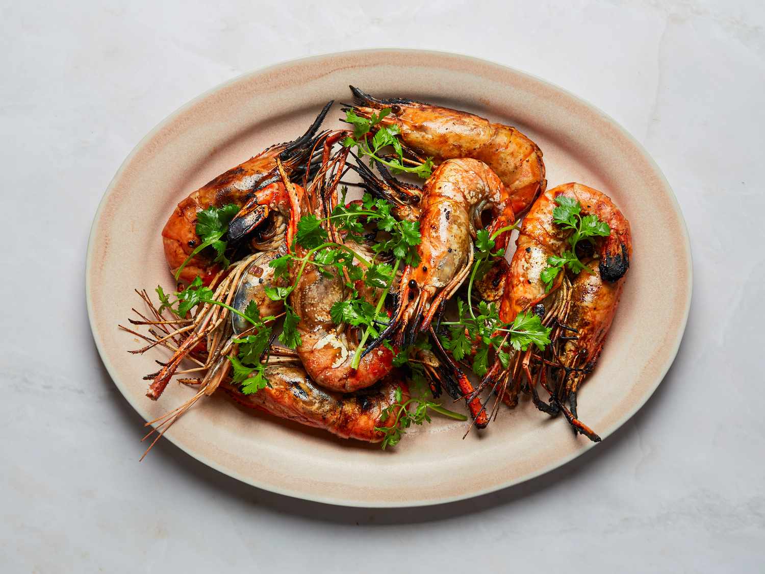 Grilled tamarindmarinated prawns served on a plate garnished with cilantro