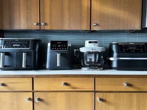 Four kitchen air fryers displayed on a countertop arranged in a row showcasing various models and designs
