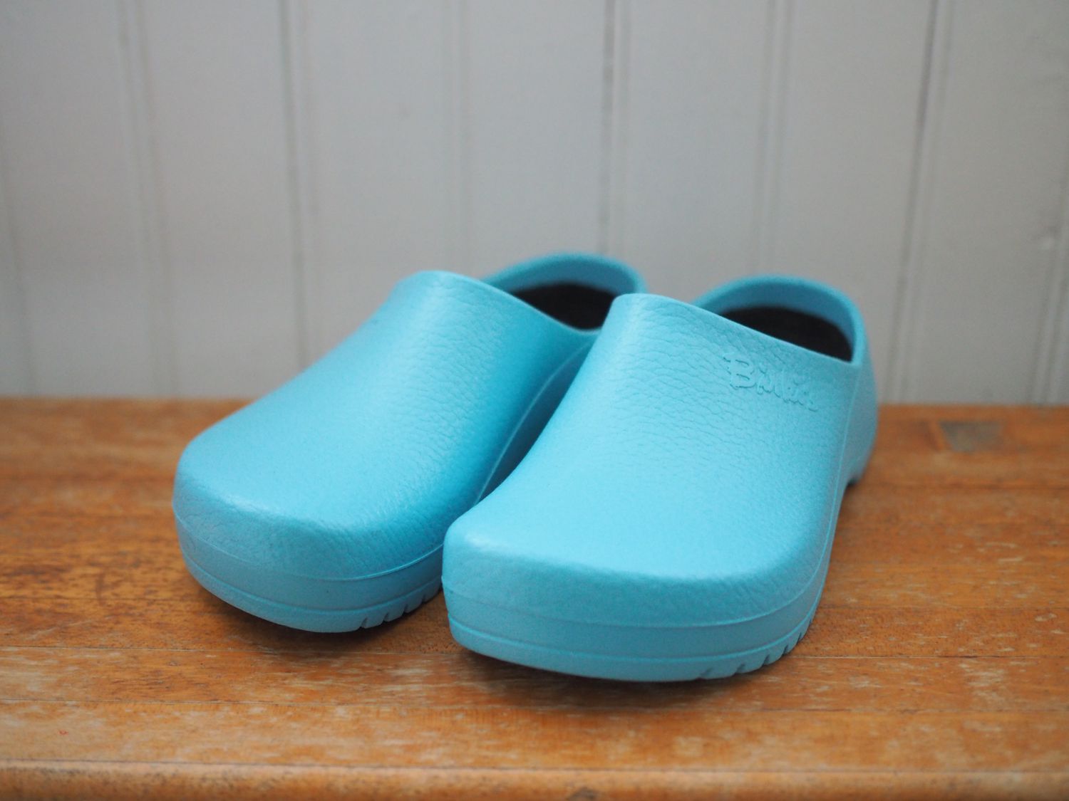 A pair of blue Birkenstock clogs on a wooden surface.