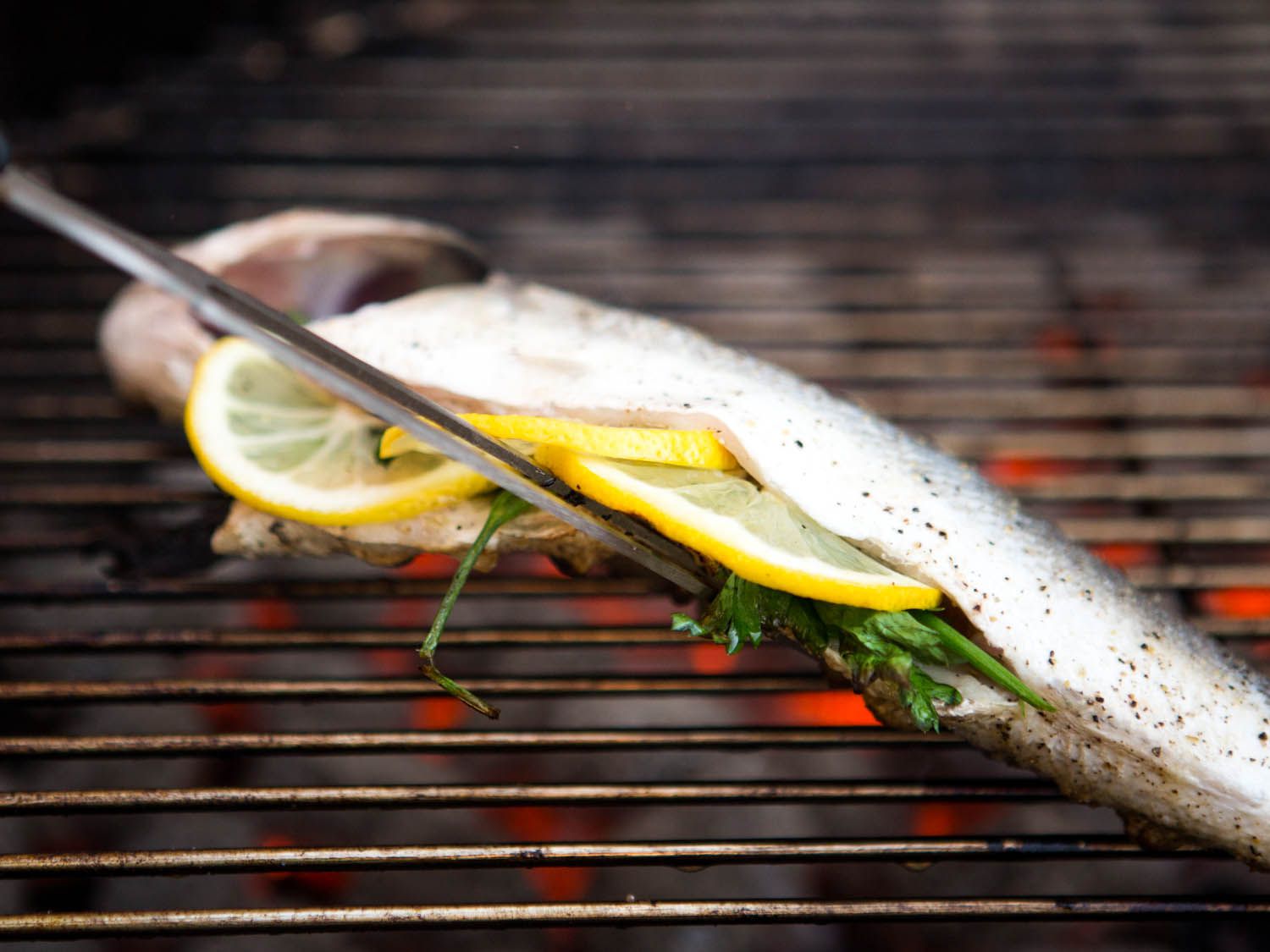 The fish is lifted off the grill grate with the fork.