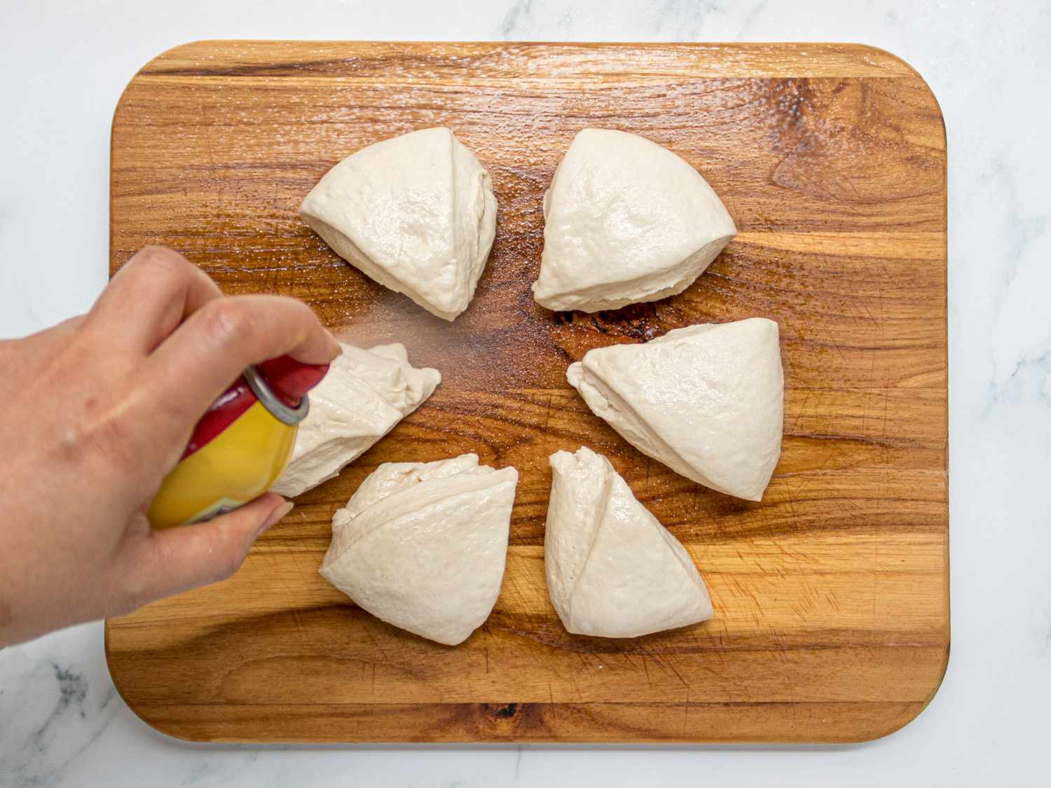 Overhead view of spraying dough triangles with cooking spray