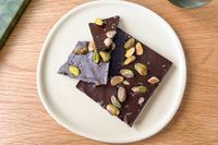 Pieces of a Compartés Salted Pistachio Chocolate Bar on a white plate