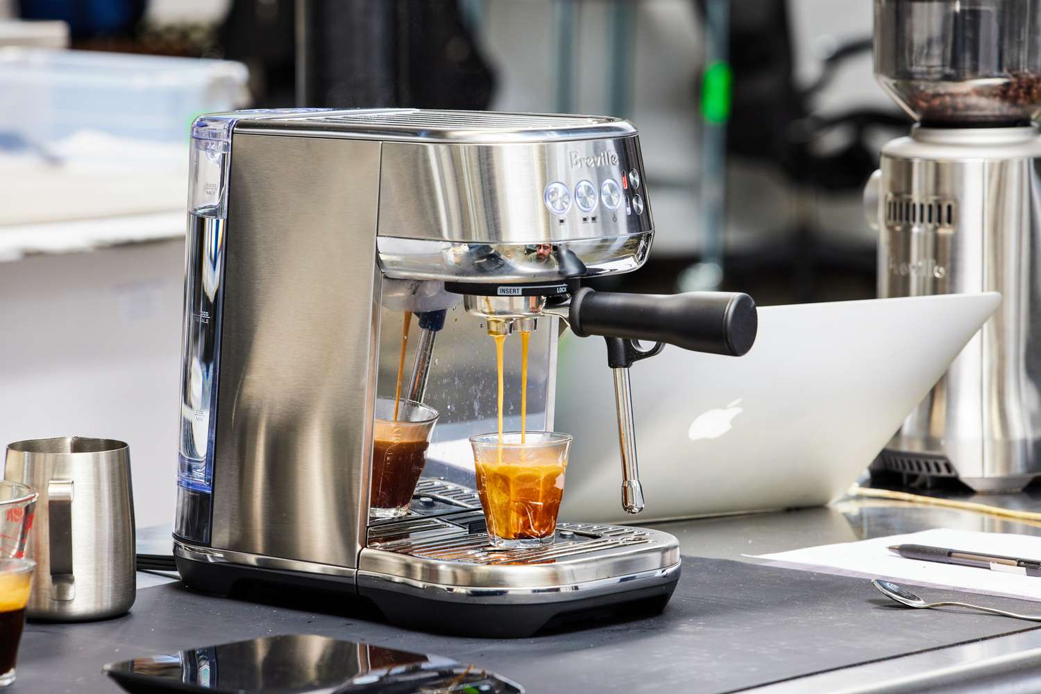 Breville Bambino Plus Espresso Machine making espresso coffee with nearby laptop