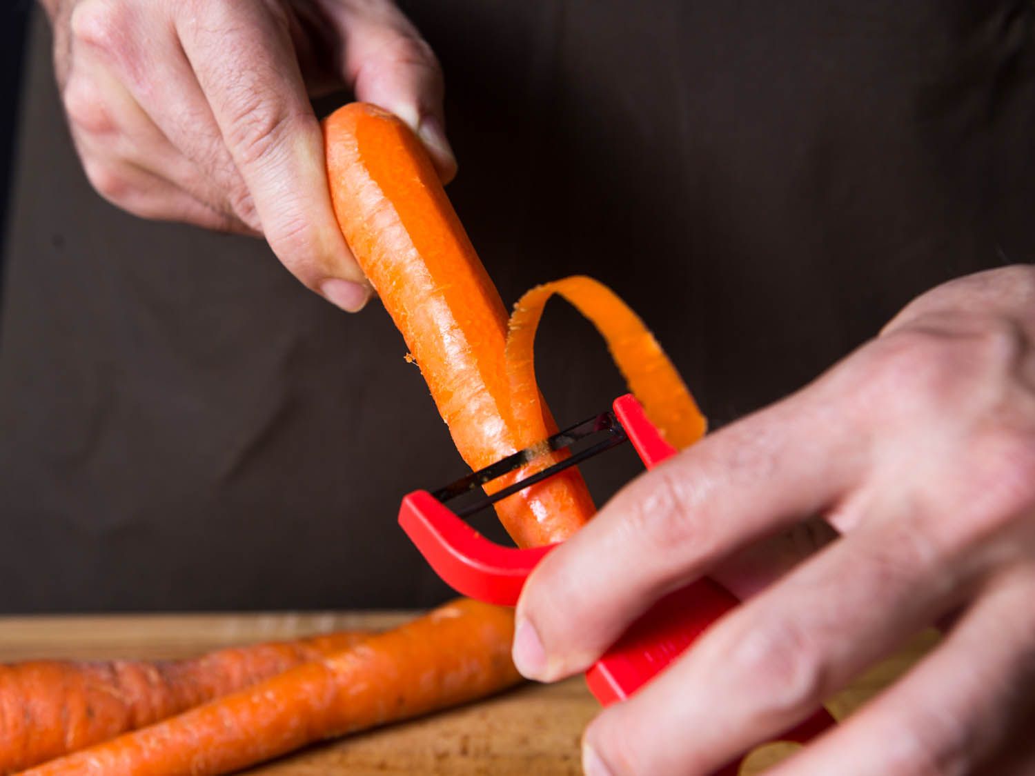 A carrot being peeled with a y-peeler