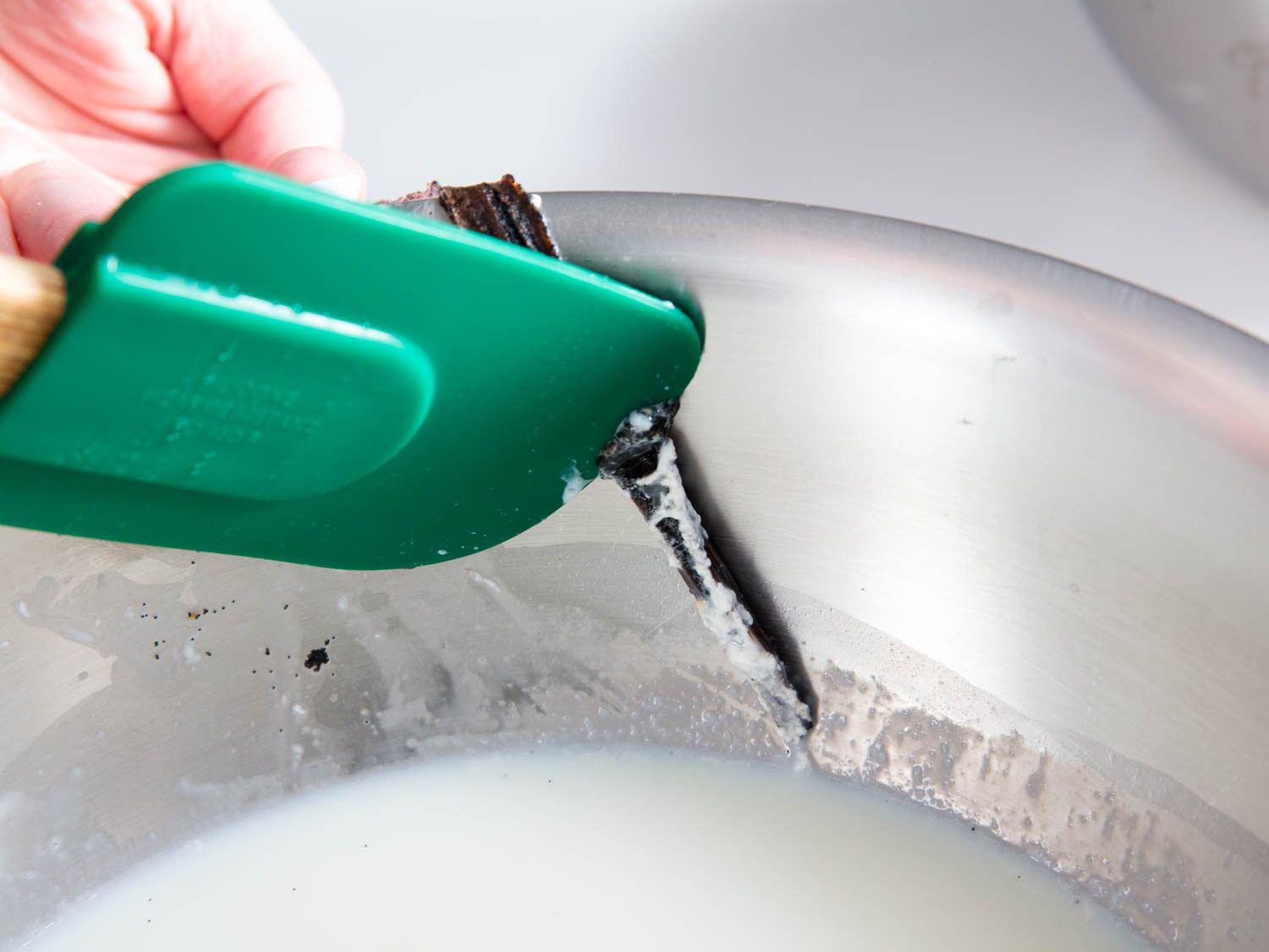 Scraping the seeds from a vanilla bean steeped in milk.