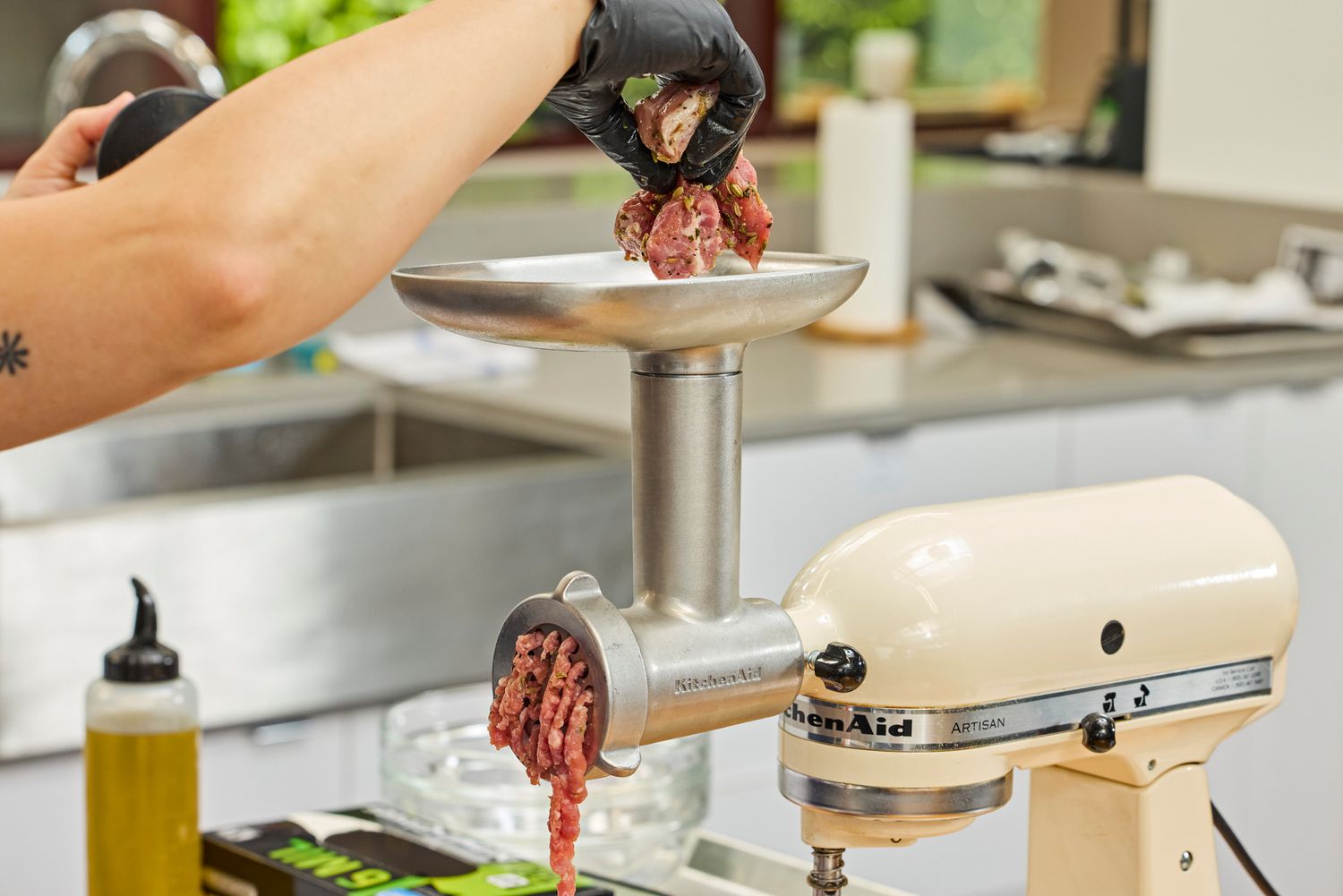 Person placing meat in food tray of KitchenAid KSMMGA Metal Food Grinder Attachment