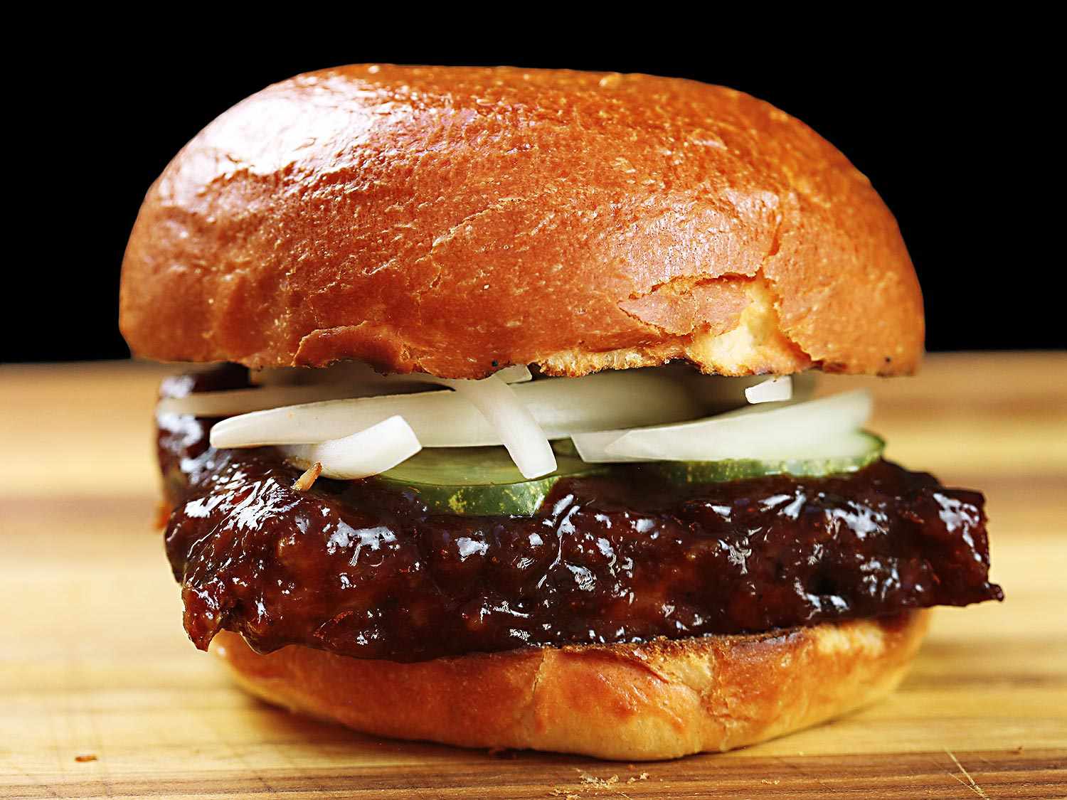 A finished homemade rib sandwich topped with onions and pickles.