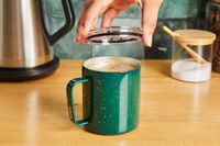 A person adding a lid to the green MiiR travel cup.