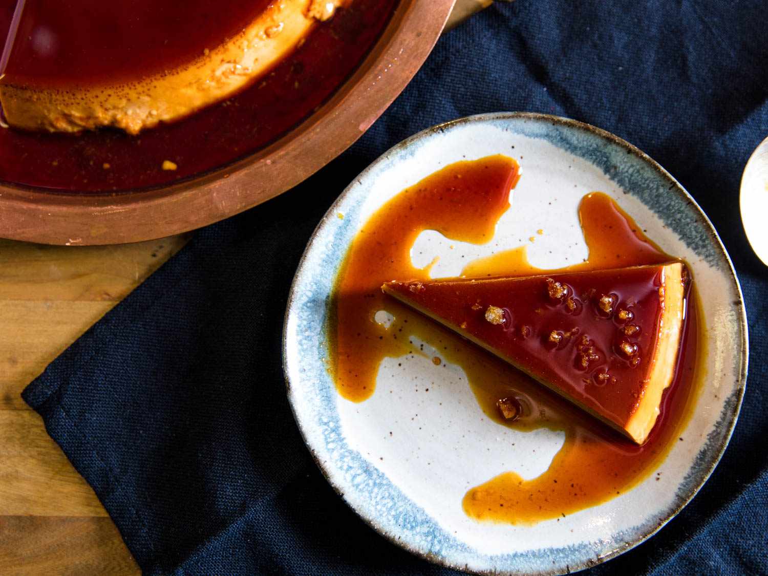 A wedge of flan on a serving plate. 