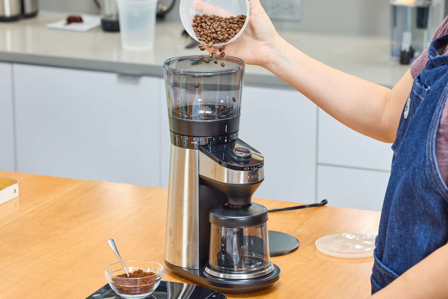 A person grounds coffee beans in the OXO Brew Conical Burr Coffee Grinder With Integrated Scale