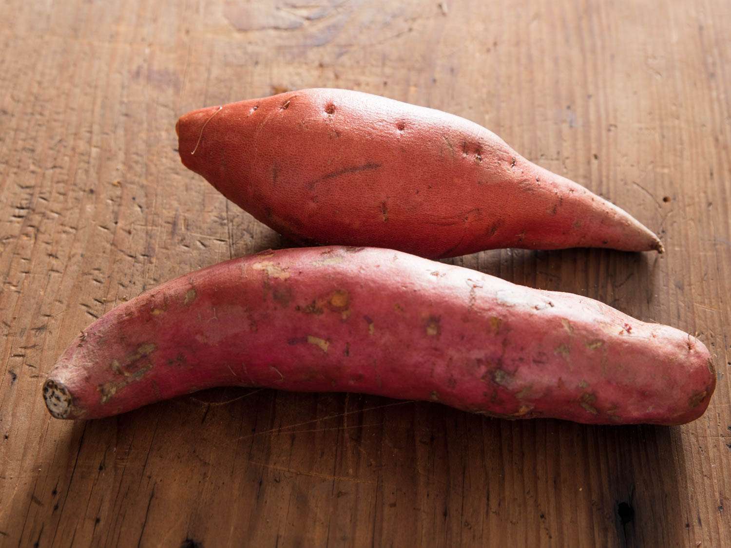 Two varieties of sweet potatoes on a cutting board
