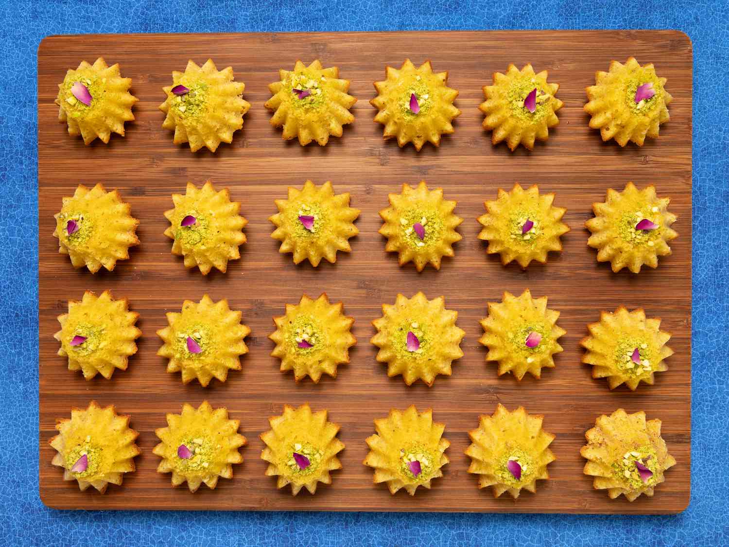 Baklava Cakes lined up on a wooden board on a blue surface 
