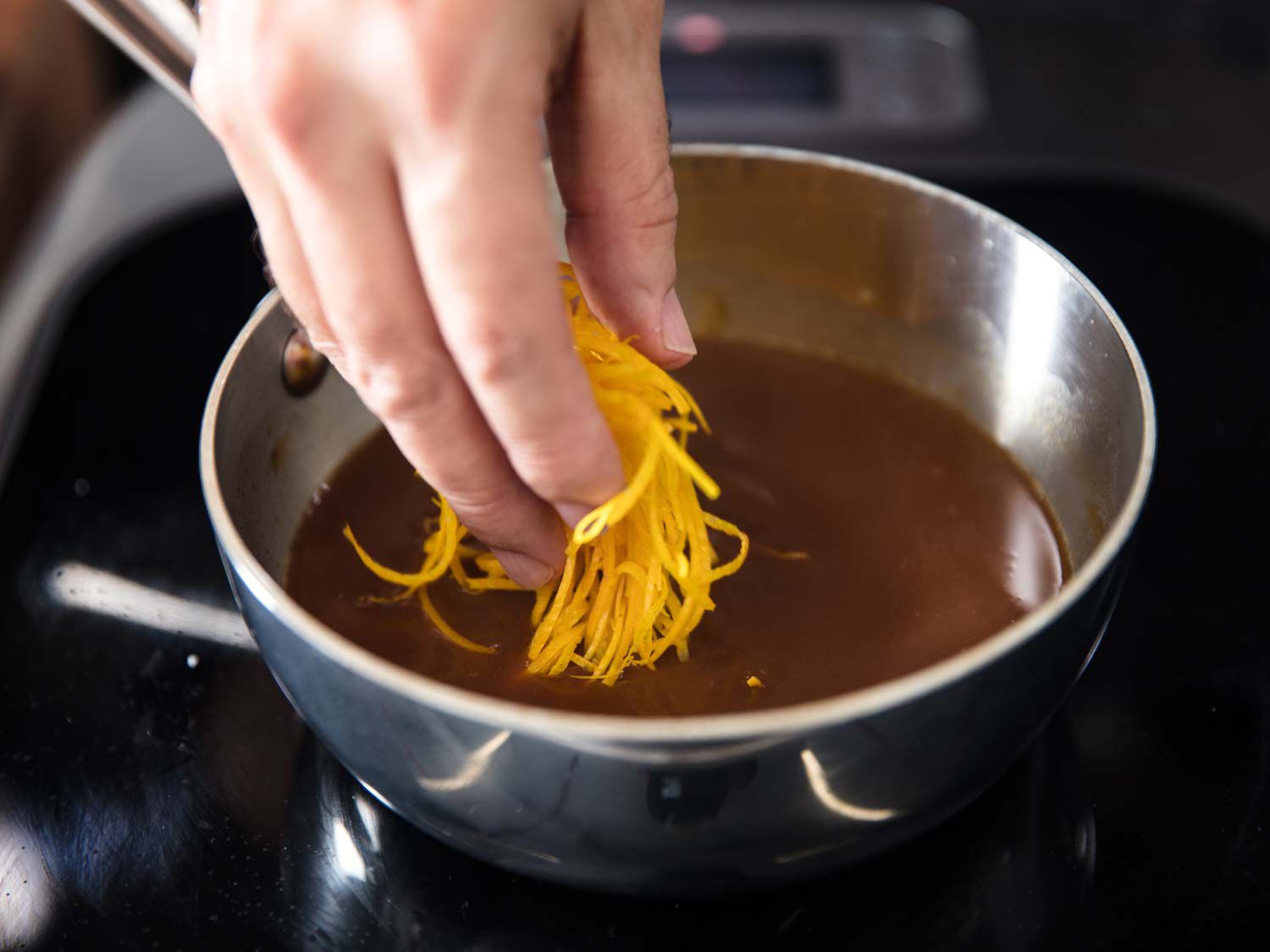 Adding blanched sliced orange zest to a saucepot of sauce for duck a l'orange 