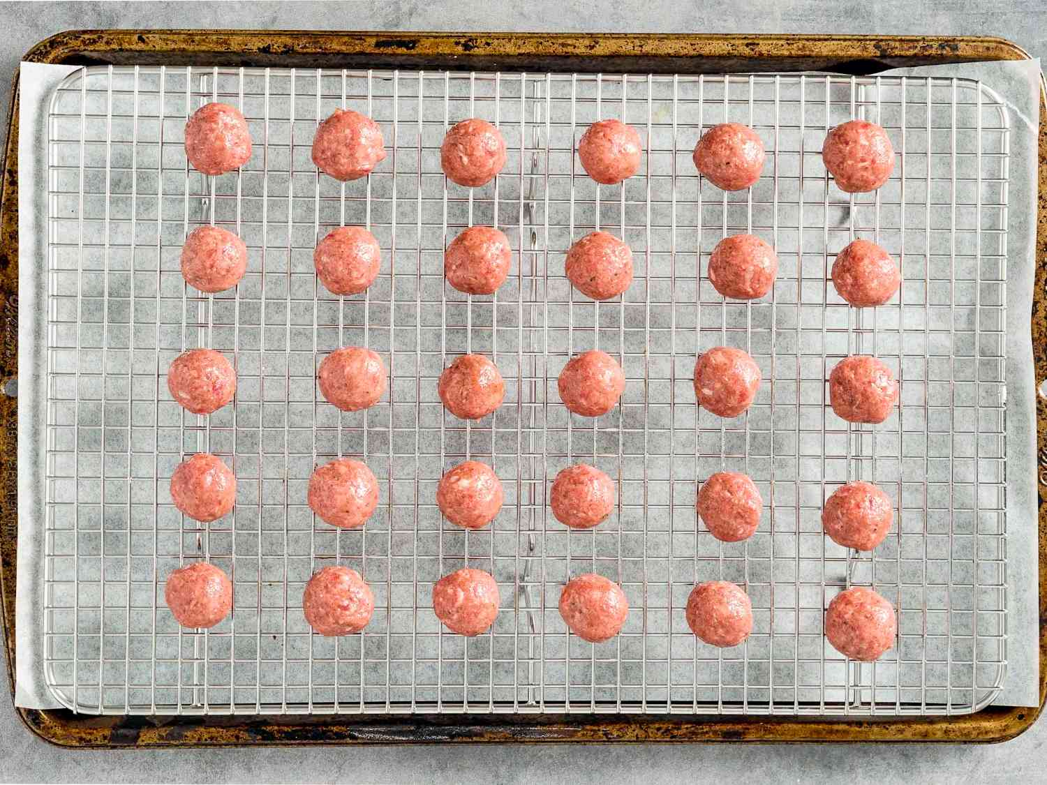 30 small meatballs on a wire rack on top of a parchment-lined baking sheet