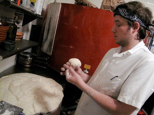 Anthony Falco, also known as Tony Calzone, shaping dough in a professional kitchen. 