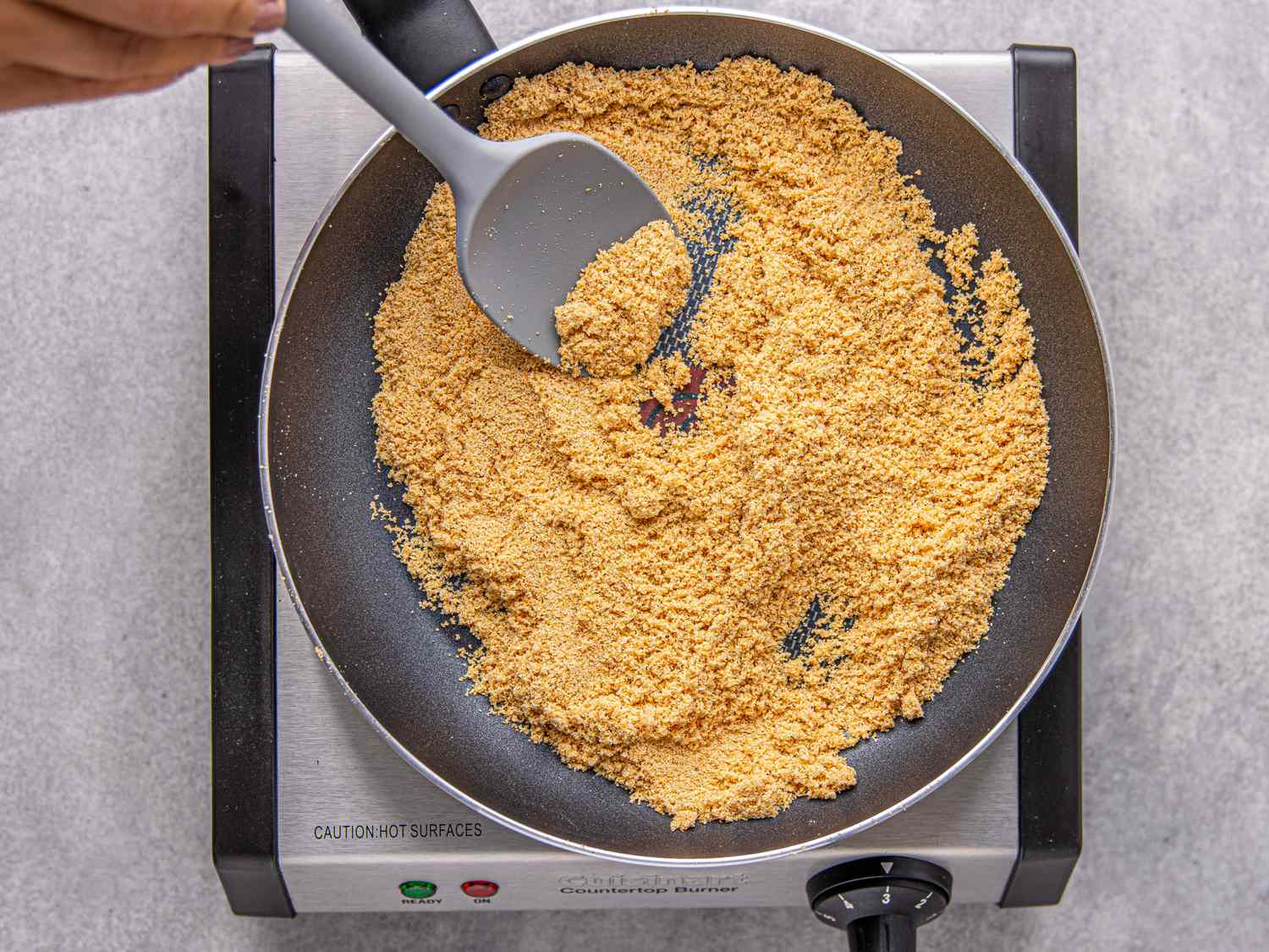 Ground ingredients being stirred in a pan on a stove