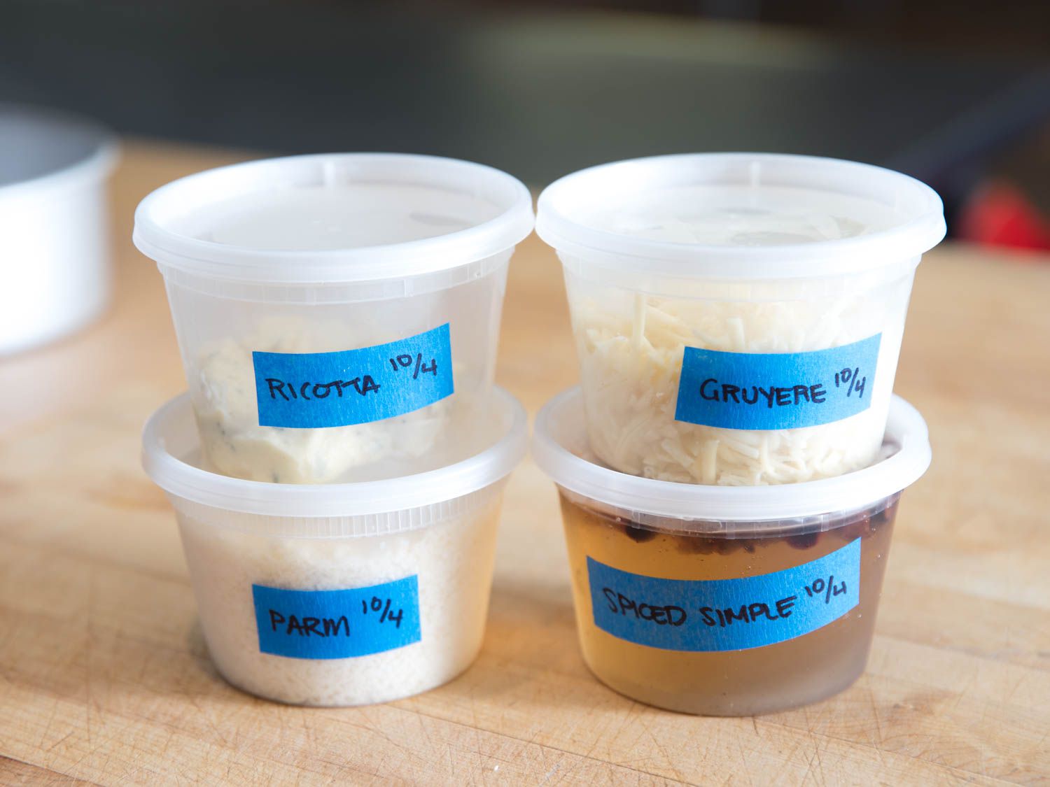 four deli containers on a wooden countertop