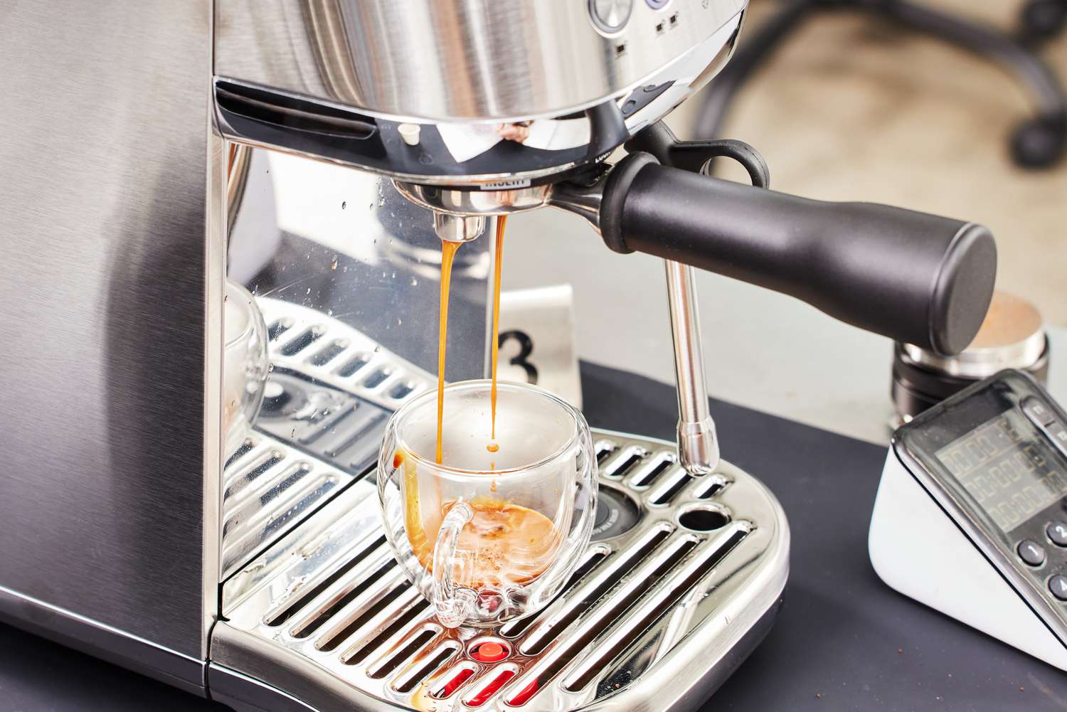 Closeup of Breville Bambino Plus Espresso Machine dispensing espresso coffee into a clear cup