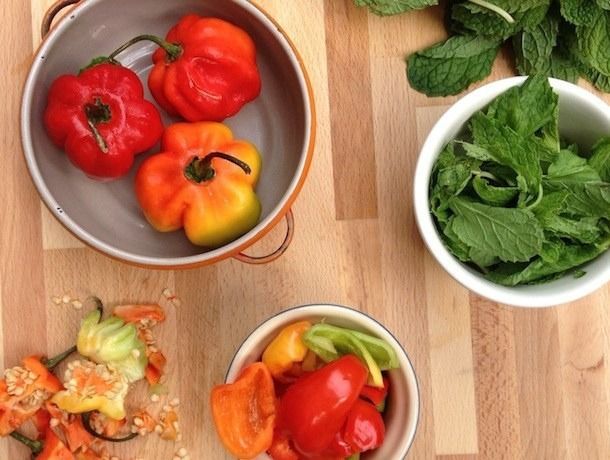 Top down view of two bowls containing Habanero peppers, some are halved. There's another bowl of mint leaves.