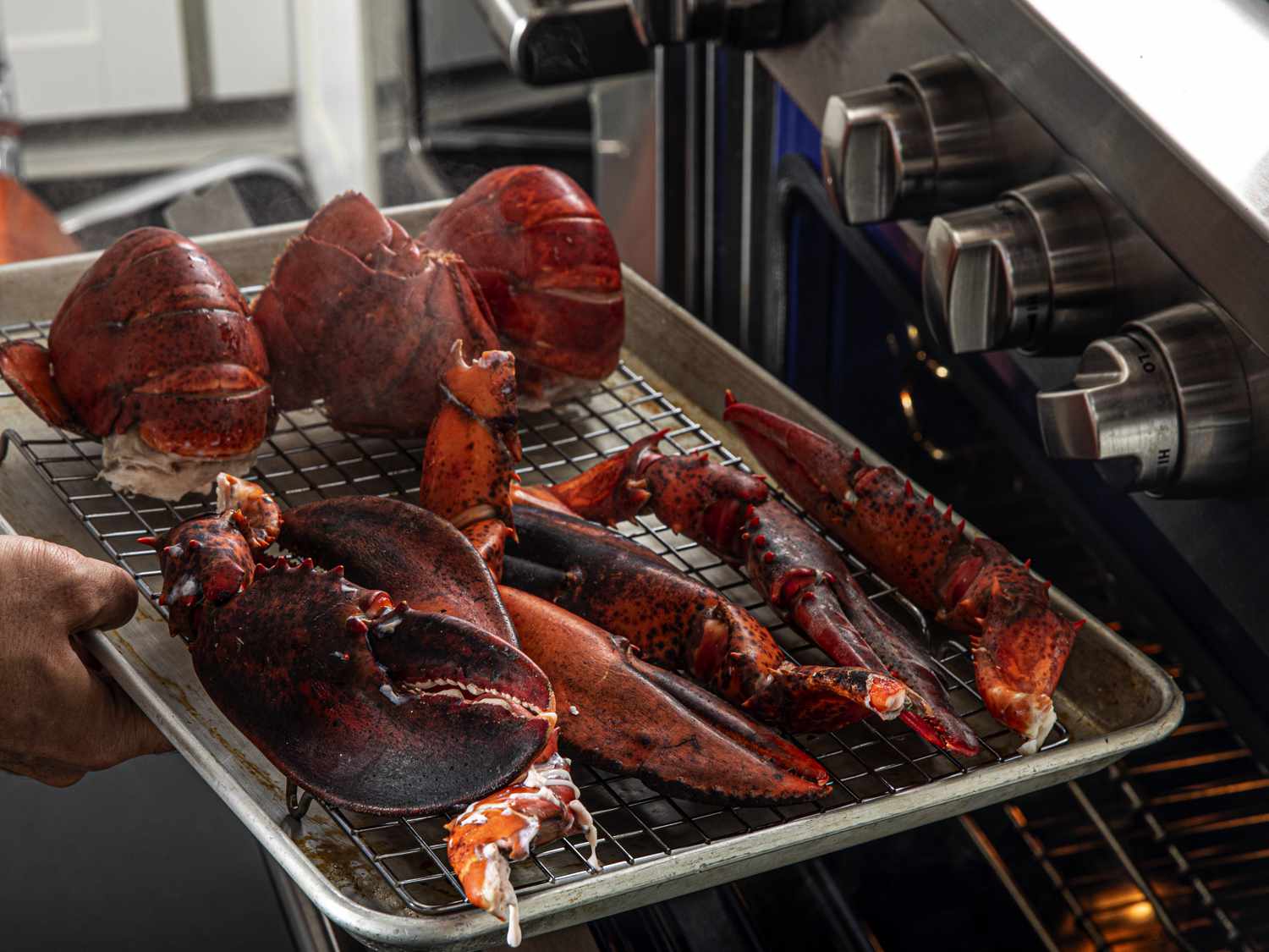 Lobster parts on a wire rack on a baking sheeting being transferred to the oven