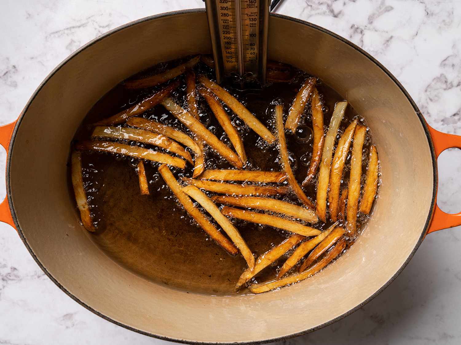Dark french fries frying in hot oil