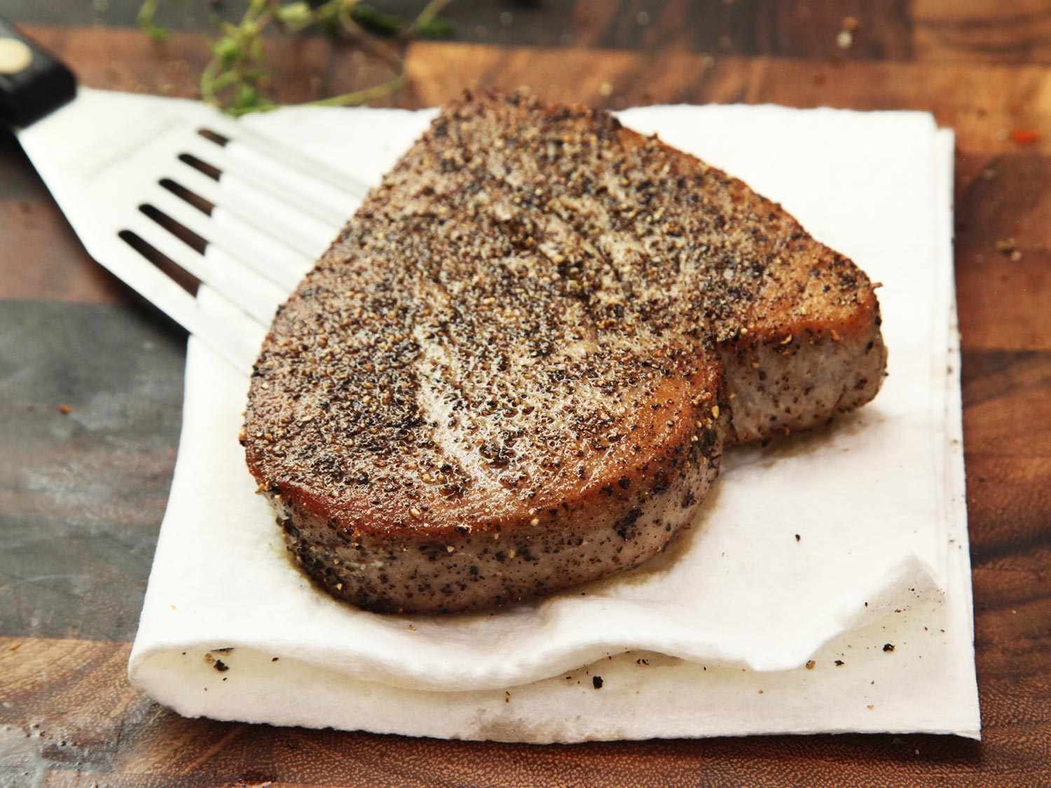 Seared tuna steak, sporting a nicely browned crust, sitting on a doubled piece of paper towel.