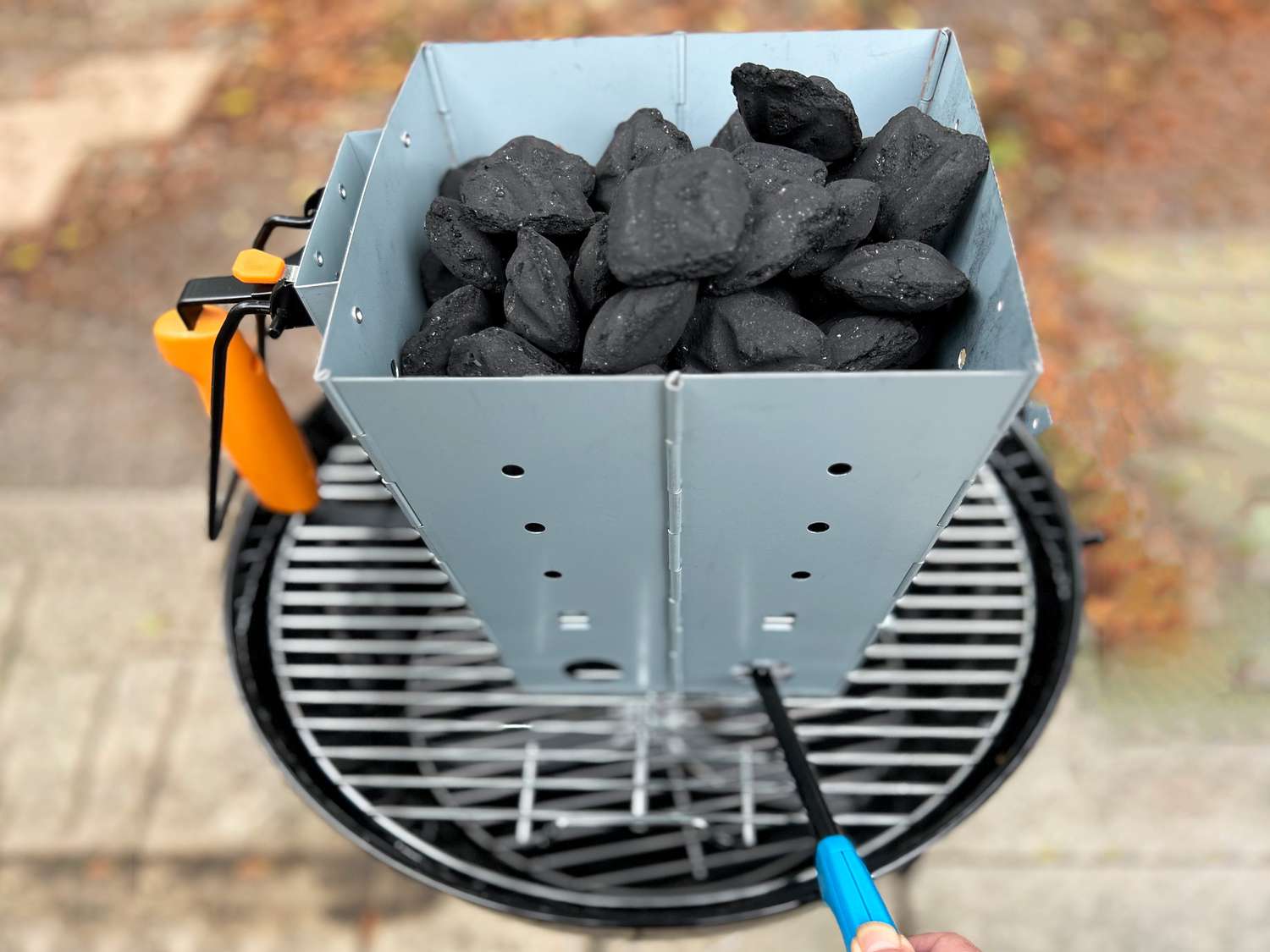 lighting a chimney starter that's sitting on top of a charcoal grill