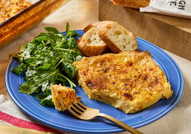 A plate with a serving of eggbased casserole side salad and slices of bread