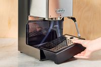 Hand adjusting the tray of the Gaggia Classic Pro Espresso Machine on a counter 