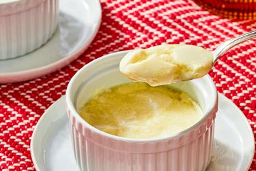 A serving of ginger pudding in a ramekin with a spoonful lifted out placed on a red patterned cloth