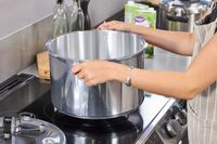 A person places the Presto 16-Quart Pressure Canner and Cooker onto a stovetop
