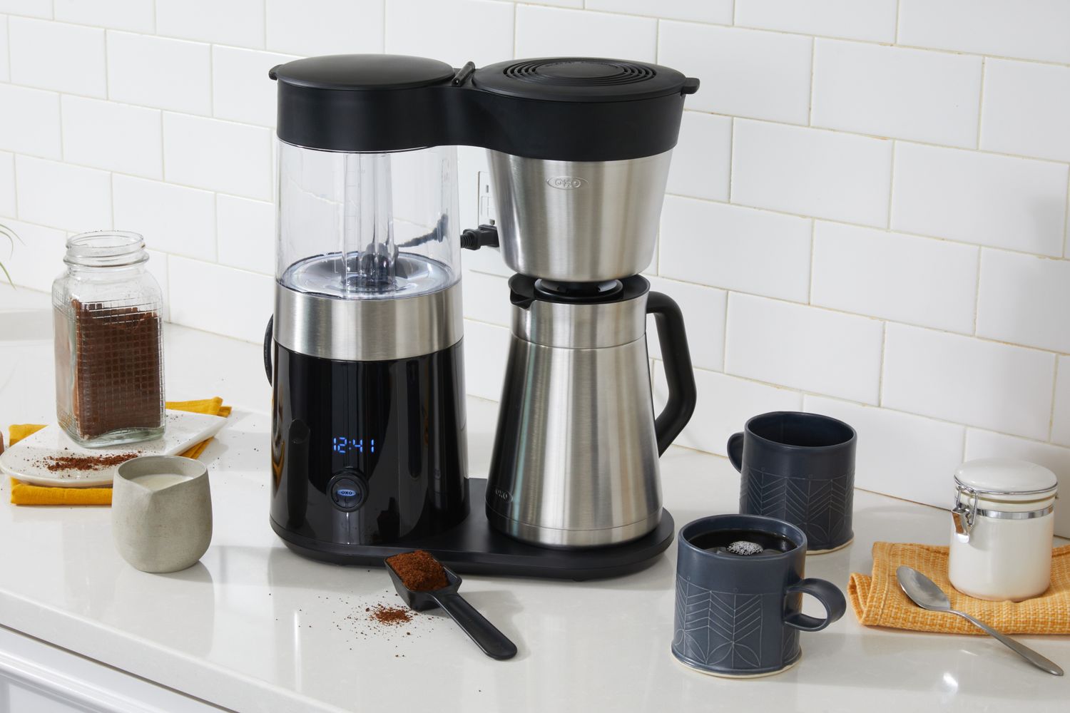 The OXO Brew 9-Cup Coffee Maker with thermal carafe on a kitchen counter surrounded by coffee mugs