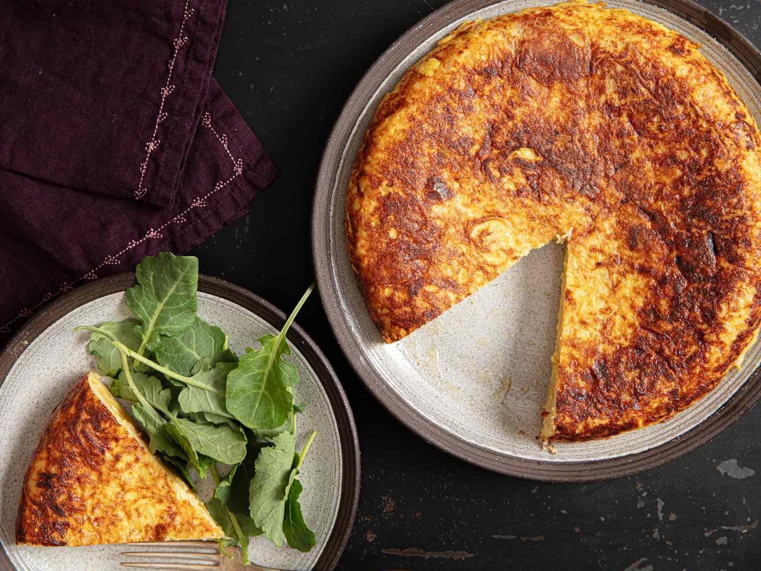A tortilla Espaola sliced on a plate a serving with greens on the side