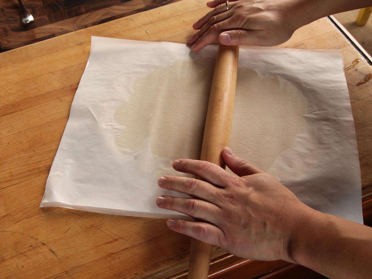 Rolling short bread dough between two layers of parchment paper.