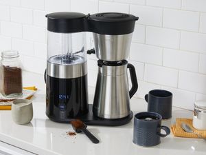The OXO Brew 9-Cup Coffee Maker with thermal carafe on a kitchen counter surrounded by coffee mugs
