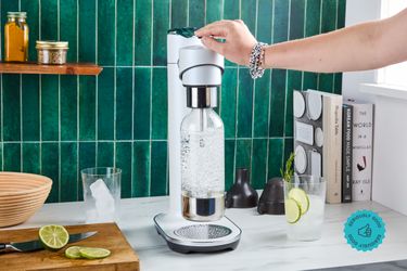 A person carbonating water with a soda maker.