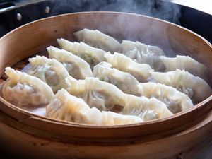 Homemade pork and scallion dumplings in a bamboo steamer. 
