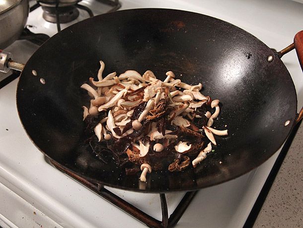 Stir-frying assorted fresh and rehydrated mushrooms in a wok