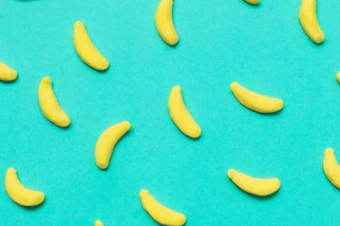 Closeup of banana-shaped candies arranged on a turquoise background.