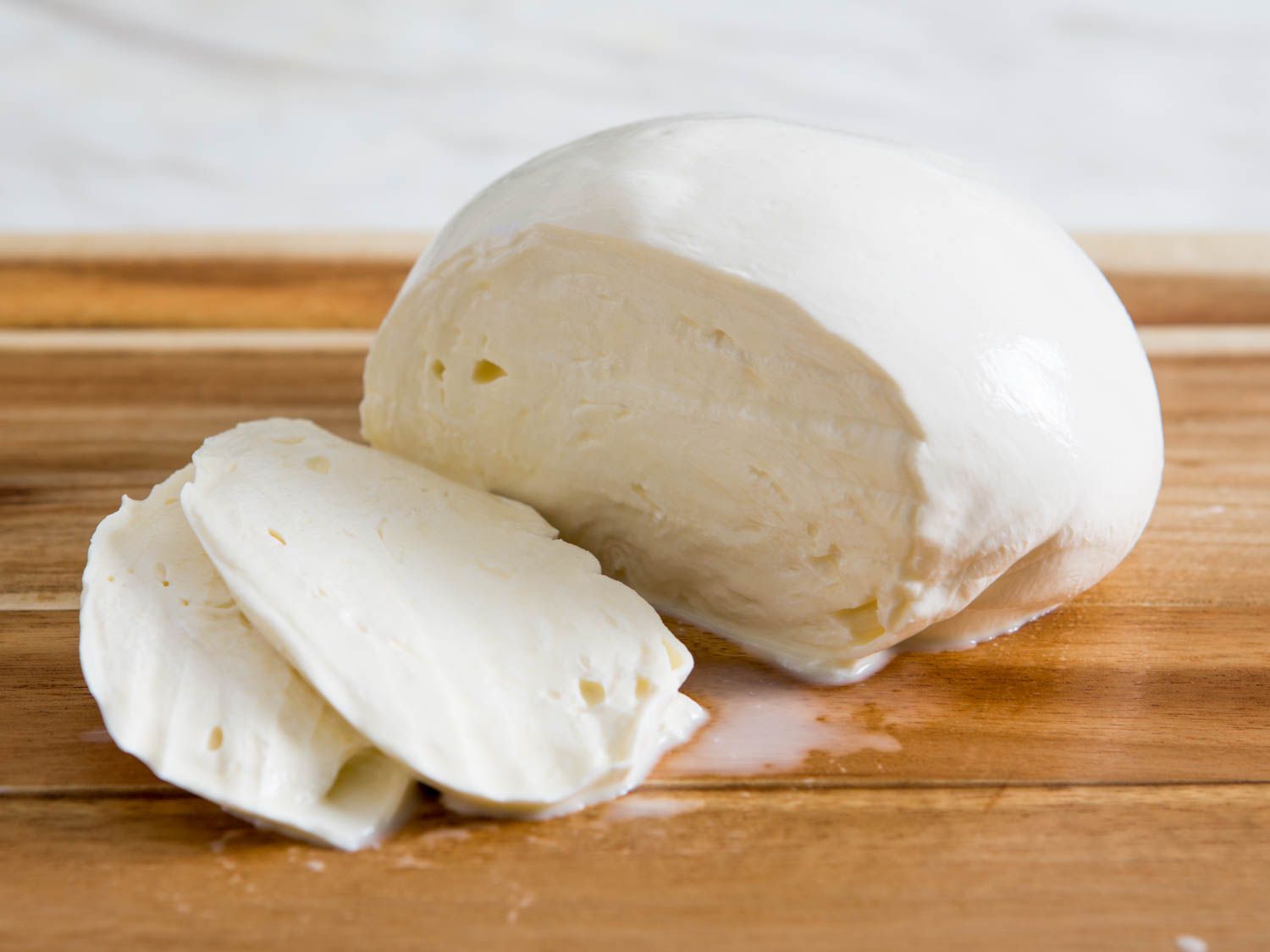 A ball of fresh mozzarella sliced open on a cutting board.