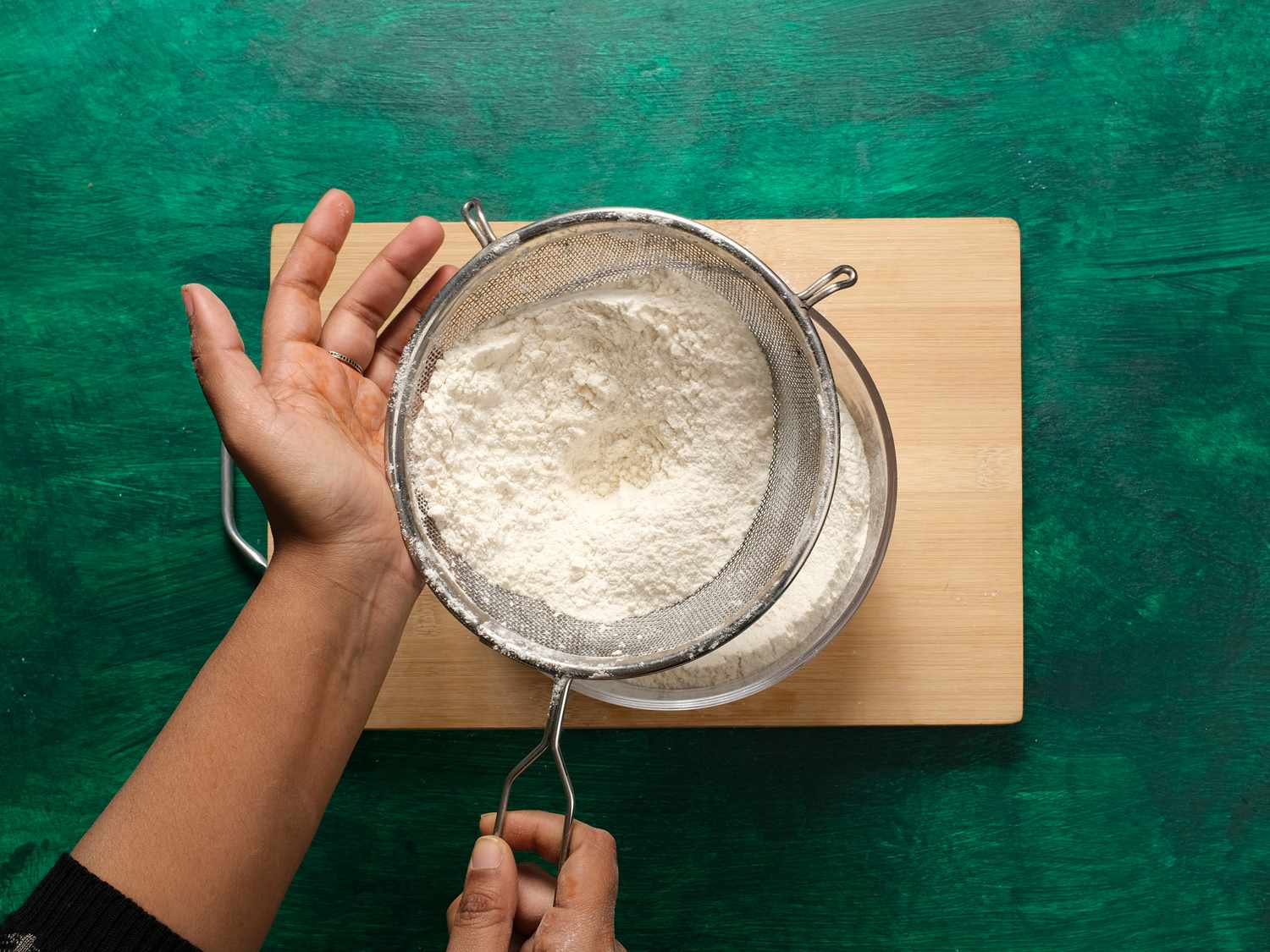 sifting flour into bowl with other dry ingredients 