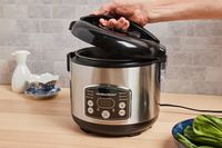 a person opening the lid to a rice cooker